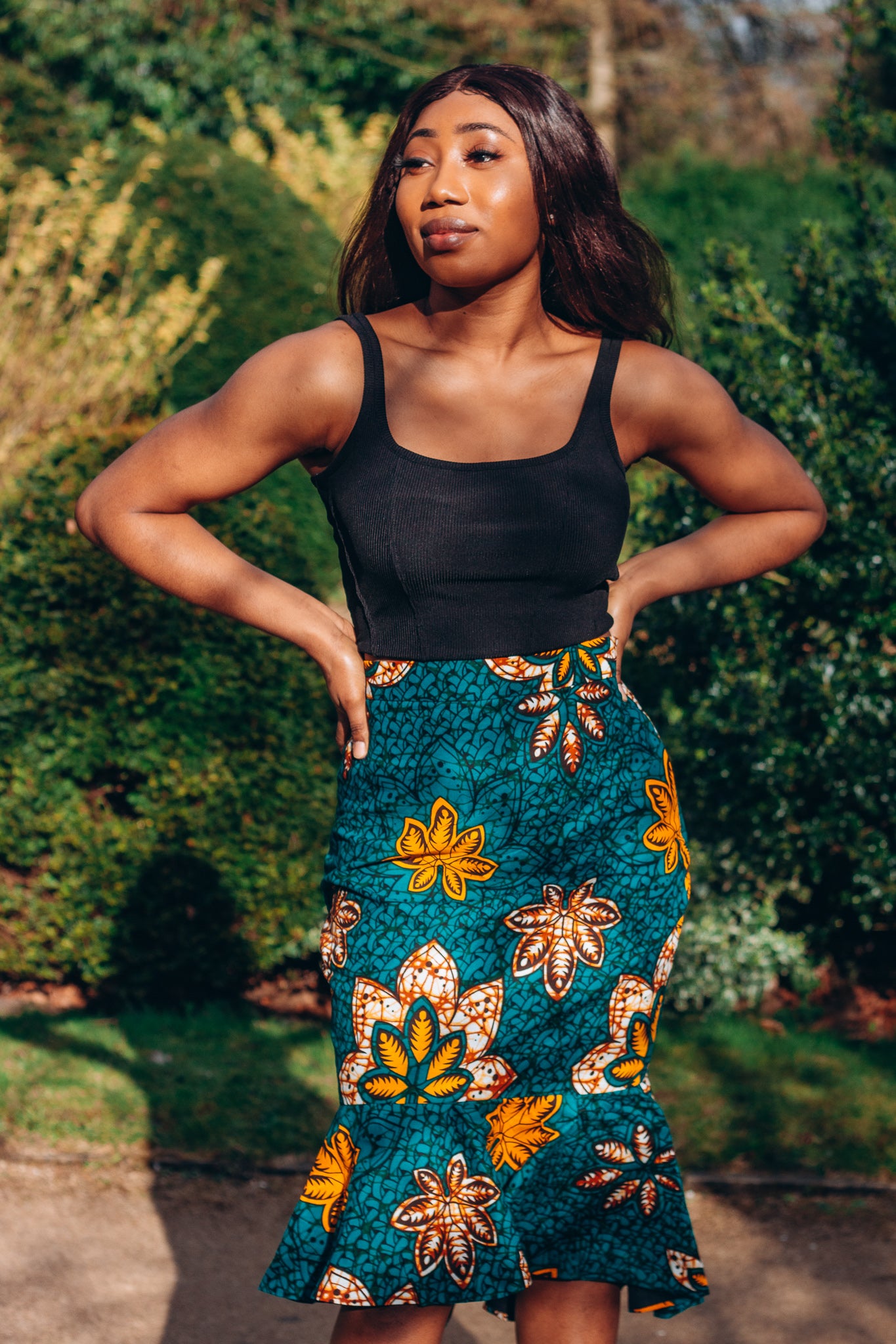 Orange, yellow, white and green African print High Waisted knee length Flared fishtail Skirt with seamed belt detailing in a floral pattern, made from sustainably sourced Ankara wax print.