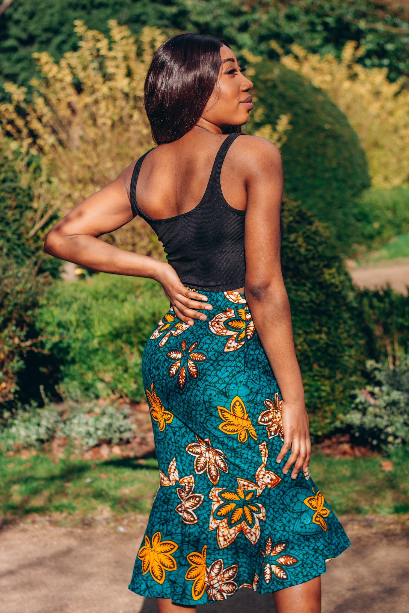 Orange, yellow, white and green African print High Waisted knee length Flared fishtail Skirt with seamed belt detailing in a floral pattern, made from sustainably sourced Ankara wax print.