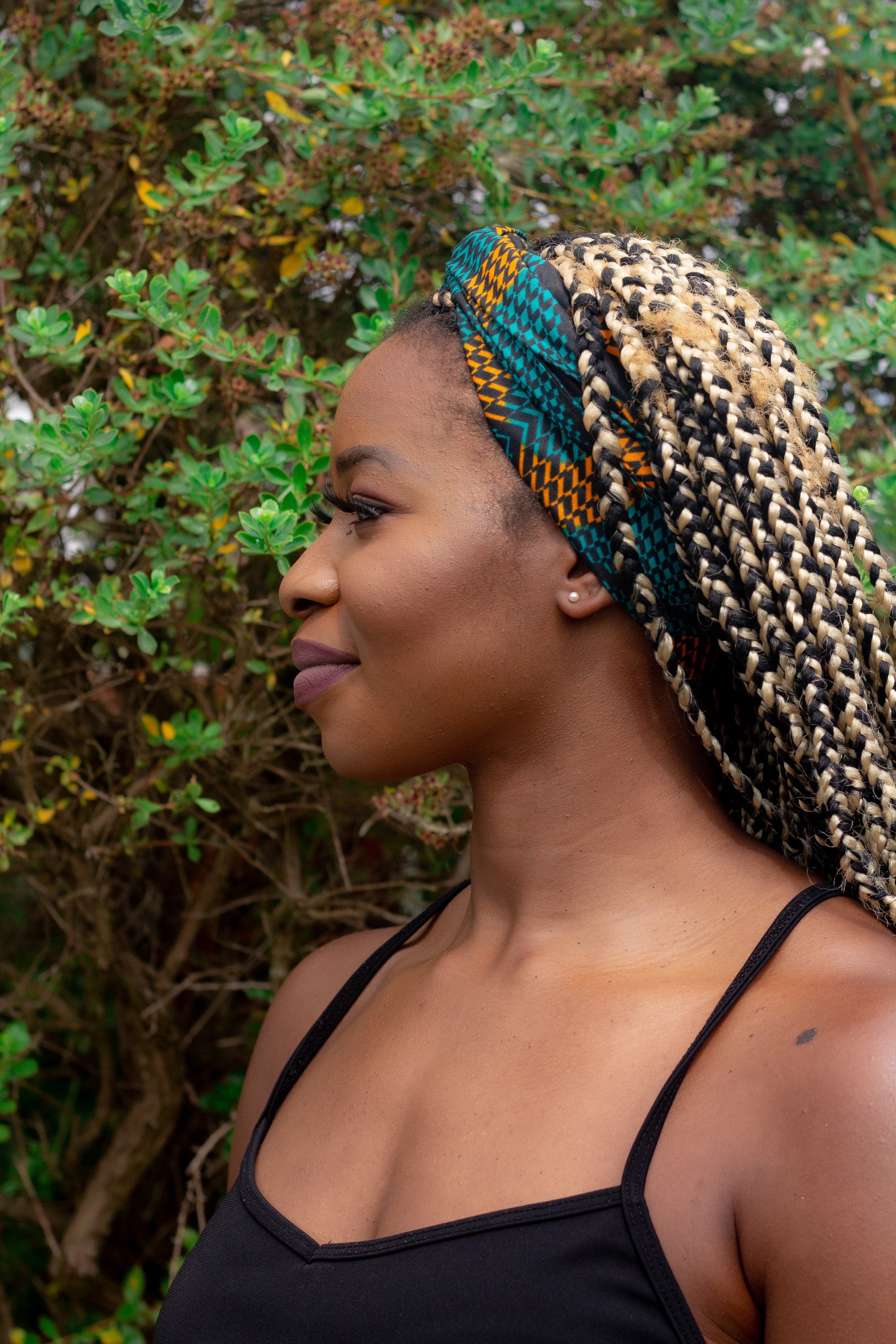 Orange, green and black African print head wrap tied as a headband in a circle geo-shaped pattern, made from sustainably sourced Ankara wax print. 