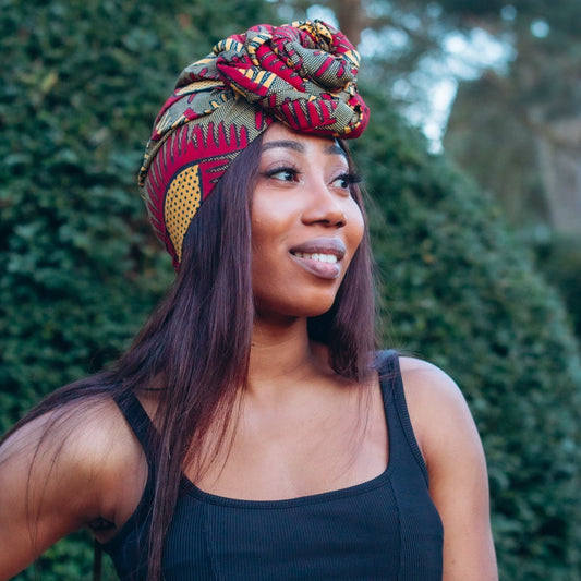Red, yellow and brown African print head wrap tied a turban in graphic floral pattern, made from sustainably sourced Ankara wax print. 