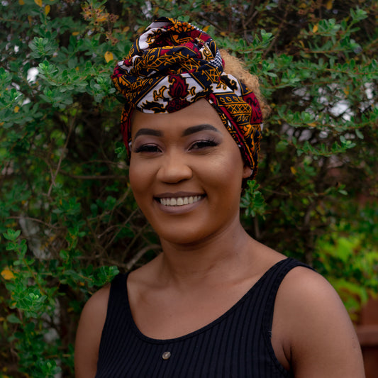 red, yellow, white, and black African print head wrap tied as a turban in floral medallion pattern, made from sustainably sourced Ankara wax print.