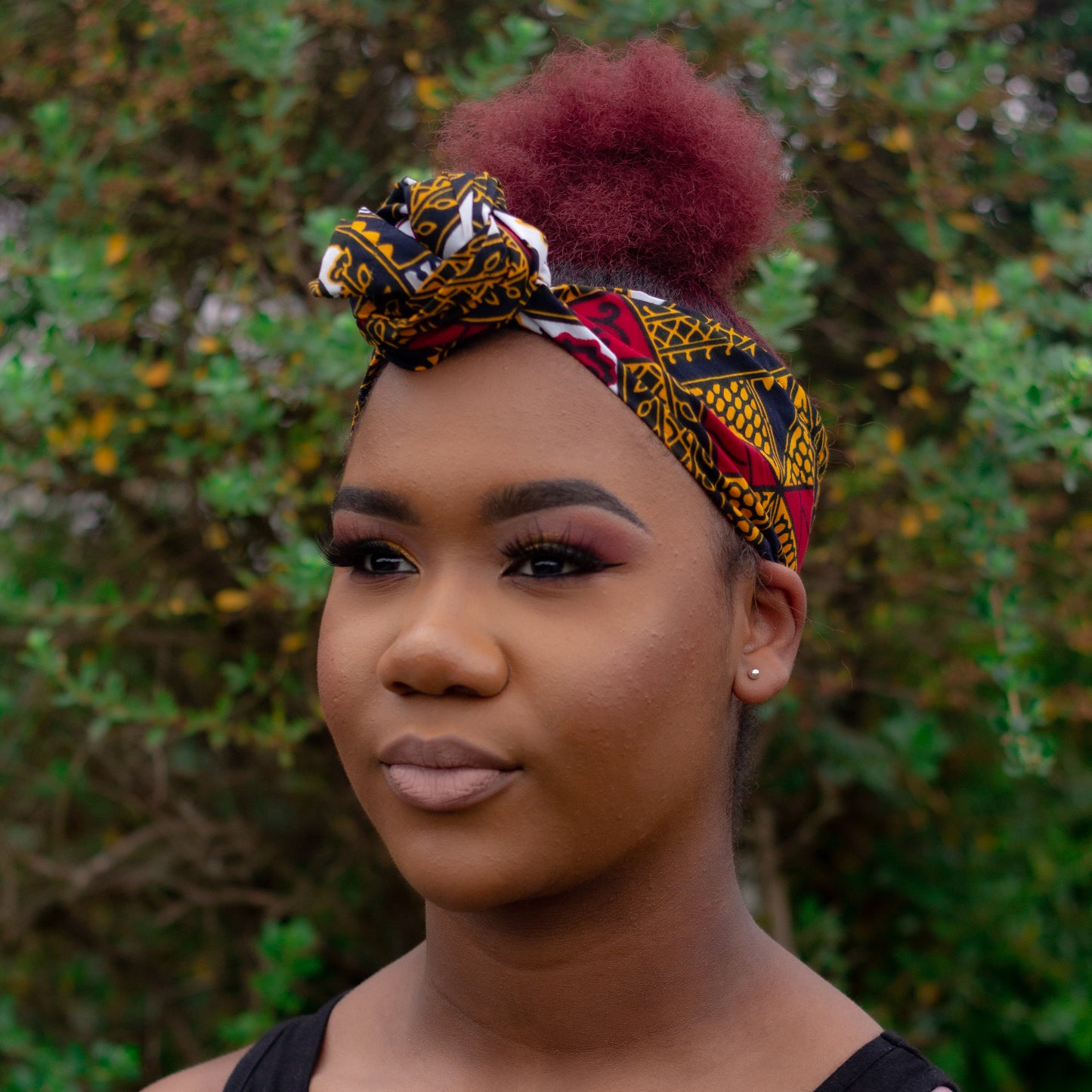 red, yellow, white, and black African print head wrap tied as a turban in floral medallion pattern, made from sustainably sourced Ankara wax print.