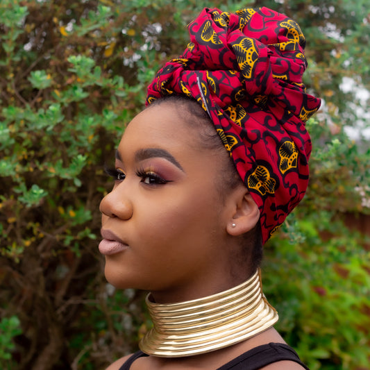 Red, yellow, and black African print head wrap tied as a turban in a floral pattern, made from sustainably sourced Ankara wax print. 