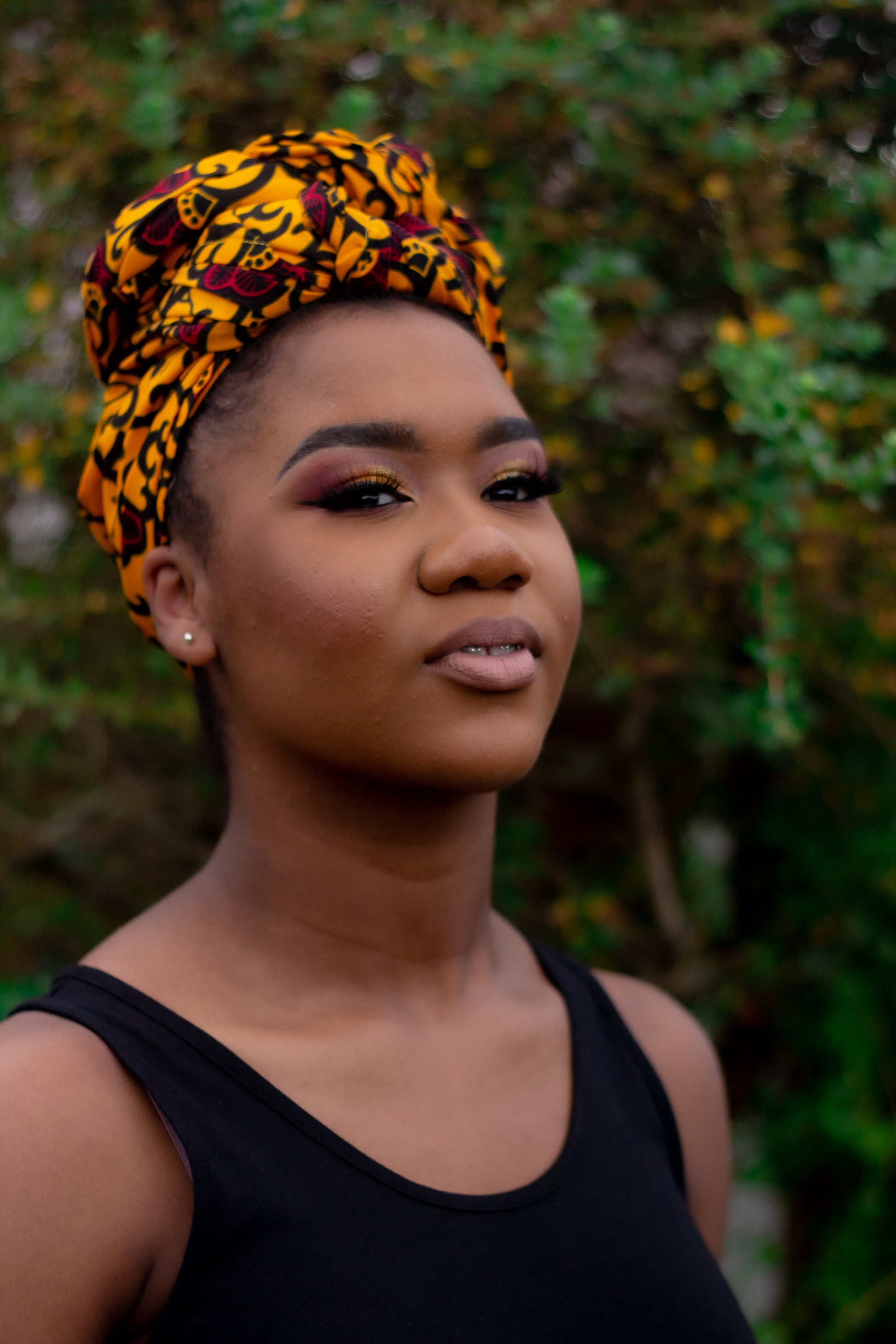 Yellow, red and black African print head wrap tied as turban in a floral pattern, made from sustainably sourced Ankara wax print.