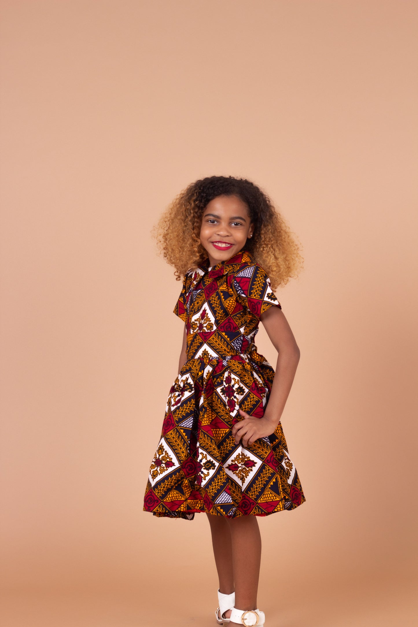  Ankara wax printed Knee length flared belted  dress with short sleeves and collared neckline in Red, yellow, white and black Squared African medallion pattern.