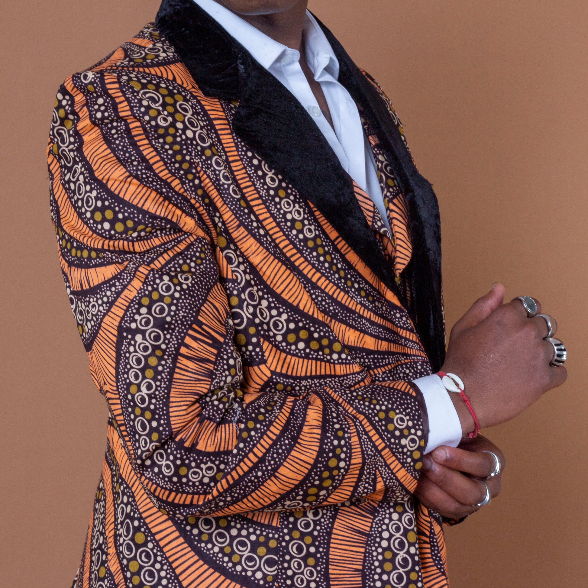 Men's blazer made from brown and orange african print ankara wax fabric finished with velvet lapels on the neckline