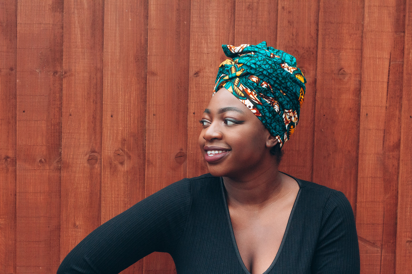 Orange, yellow, white and green African print head wrap tied a turban in a floral pattern, made from sustainably sourced Ankara wax print. 