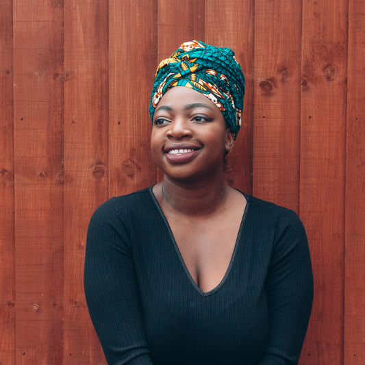 Orange, yellow, white and green African print head wrap tied a turban in a floral pattern, made from sustainably sourced Ankara wax print. 