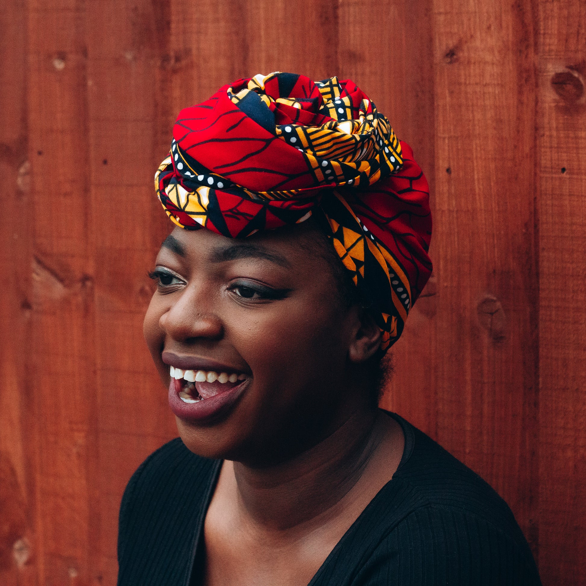 red, yellow, white, and black African print head wrap tied as a turban in a graphic pattern, made from sustainably sourced Ankara wax print.