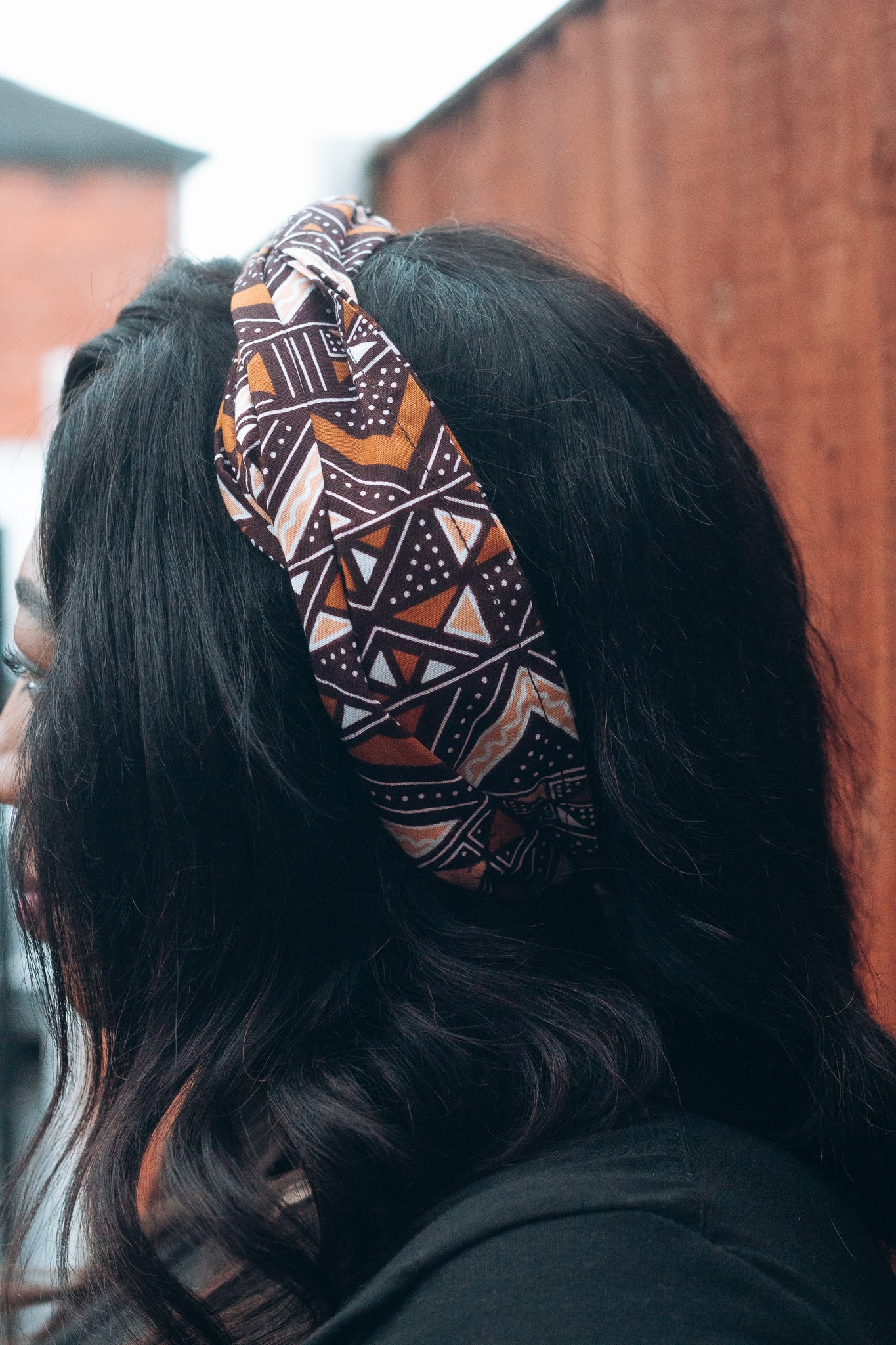 Brown, black and white African print head wrap tied a headband in graphic triangle pattern, made from sustainably sourced Ankara wax print. 