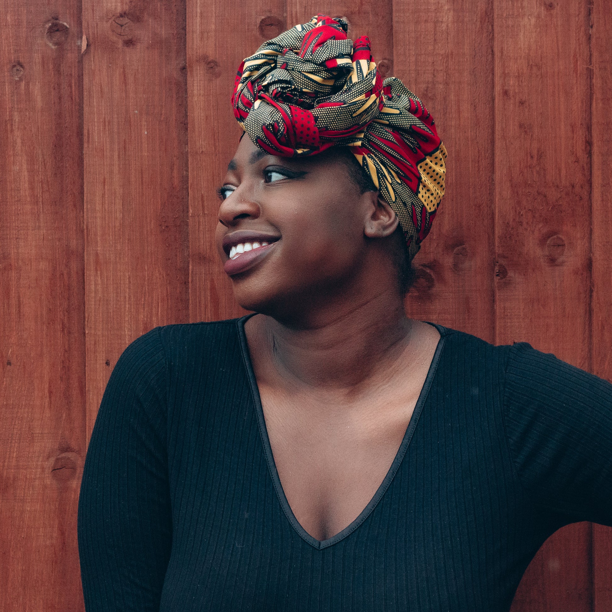 Brown, red and yellow African print head wrap tied a turban in textured pattern, made from sustainably sourced Ankara wax print. 