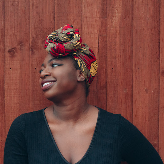 Brown, red and yellow African print head wrap tied a turban in textured pattern, made from sustainably sourced Ankara wax print. 