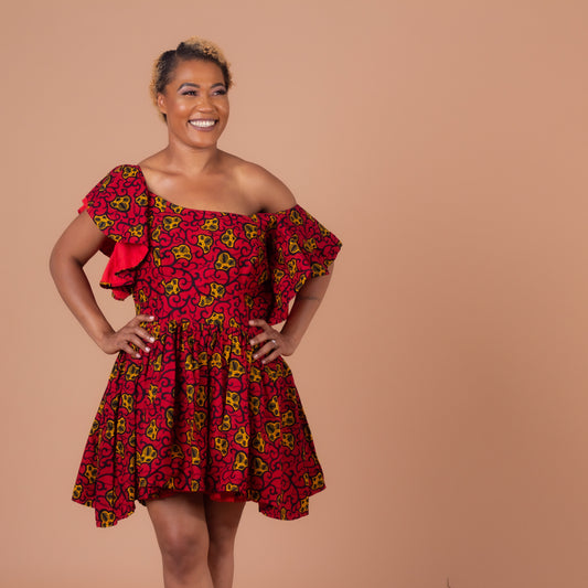   Red, yellow and black Ana African Ankara wax print in a floral pattern on a off the shoulder panelled ruffled skater dress with flared quarter sleeves with pockets on each side.