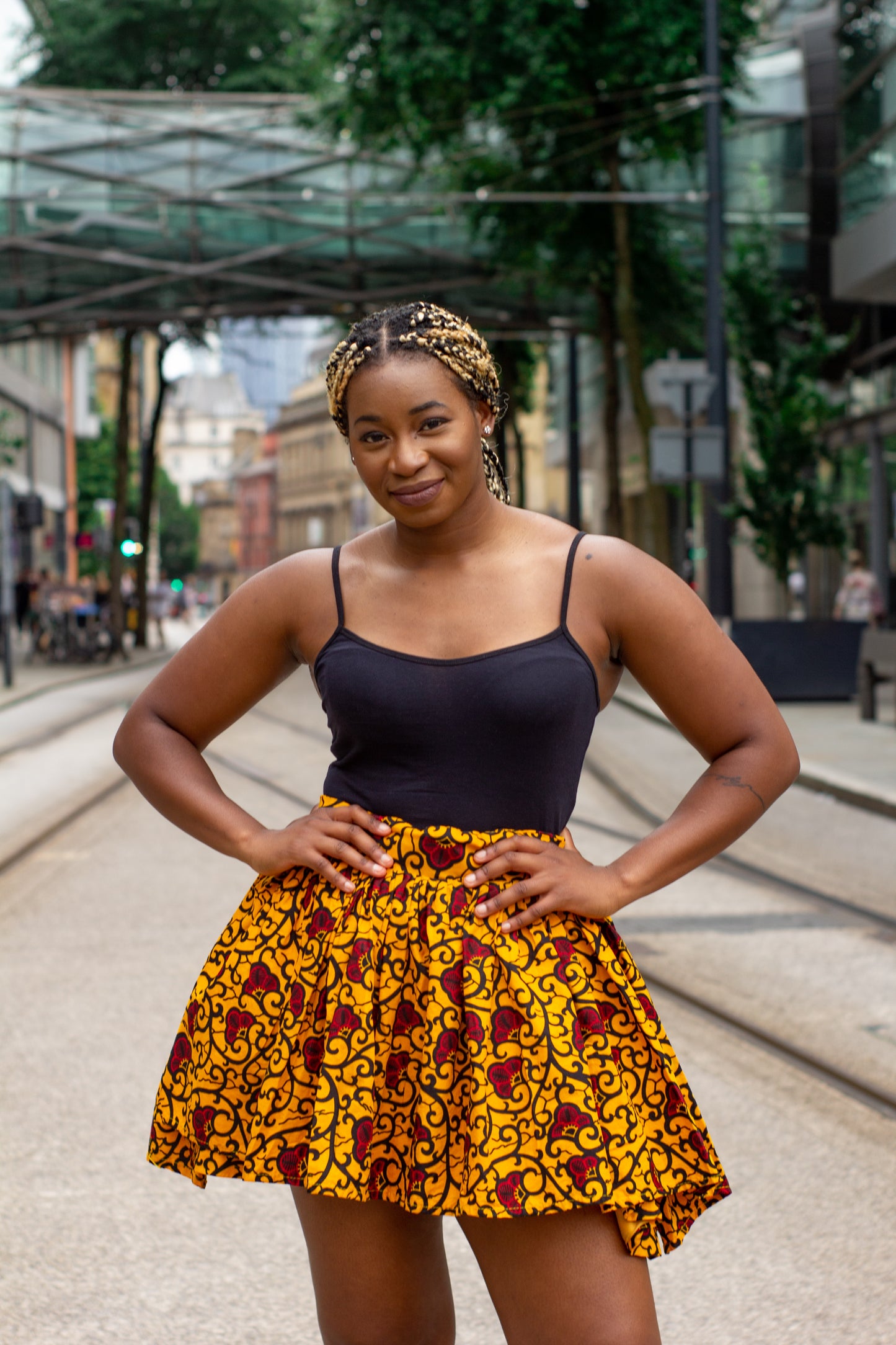 Yellow, red and black African print knee length pleated skater skirt in floral pattern, made from sustainably sourced Ankara wax print with belted seam detail.