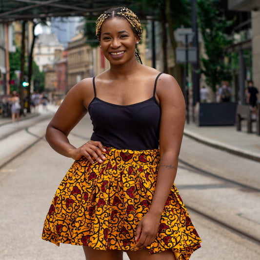 Yellow, red and black African print knee length pleated skater skirt in floral pattern, made from sustainably source Ankara wax print with belted seam detail.