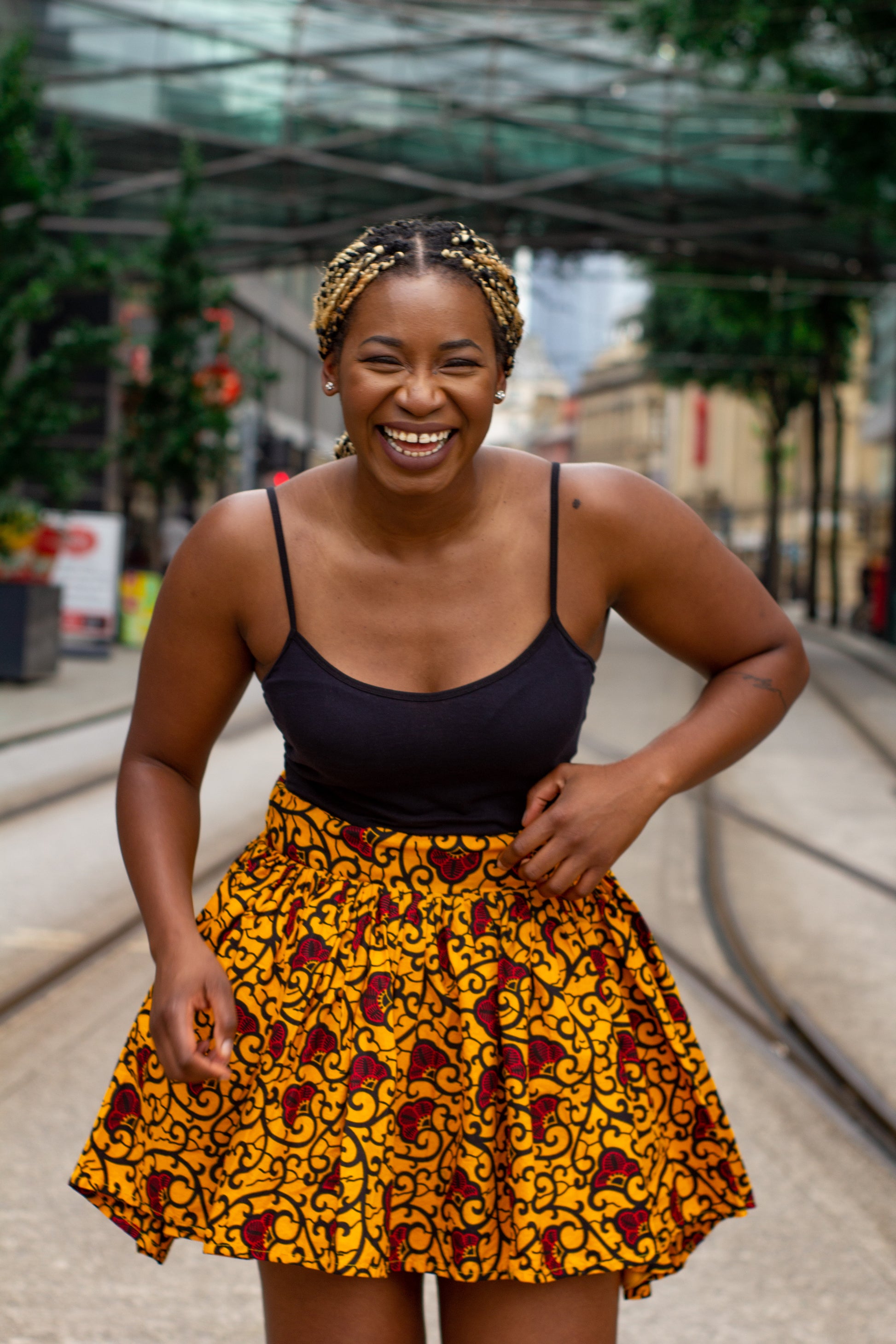 Yellow, red and black African print knee length pleated skater skirt in floral pattern, made from sustainably sourced Ankara wax print with belted seam detail.