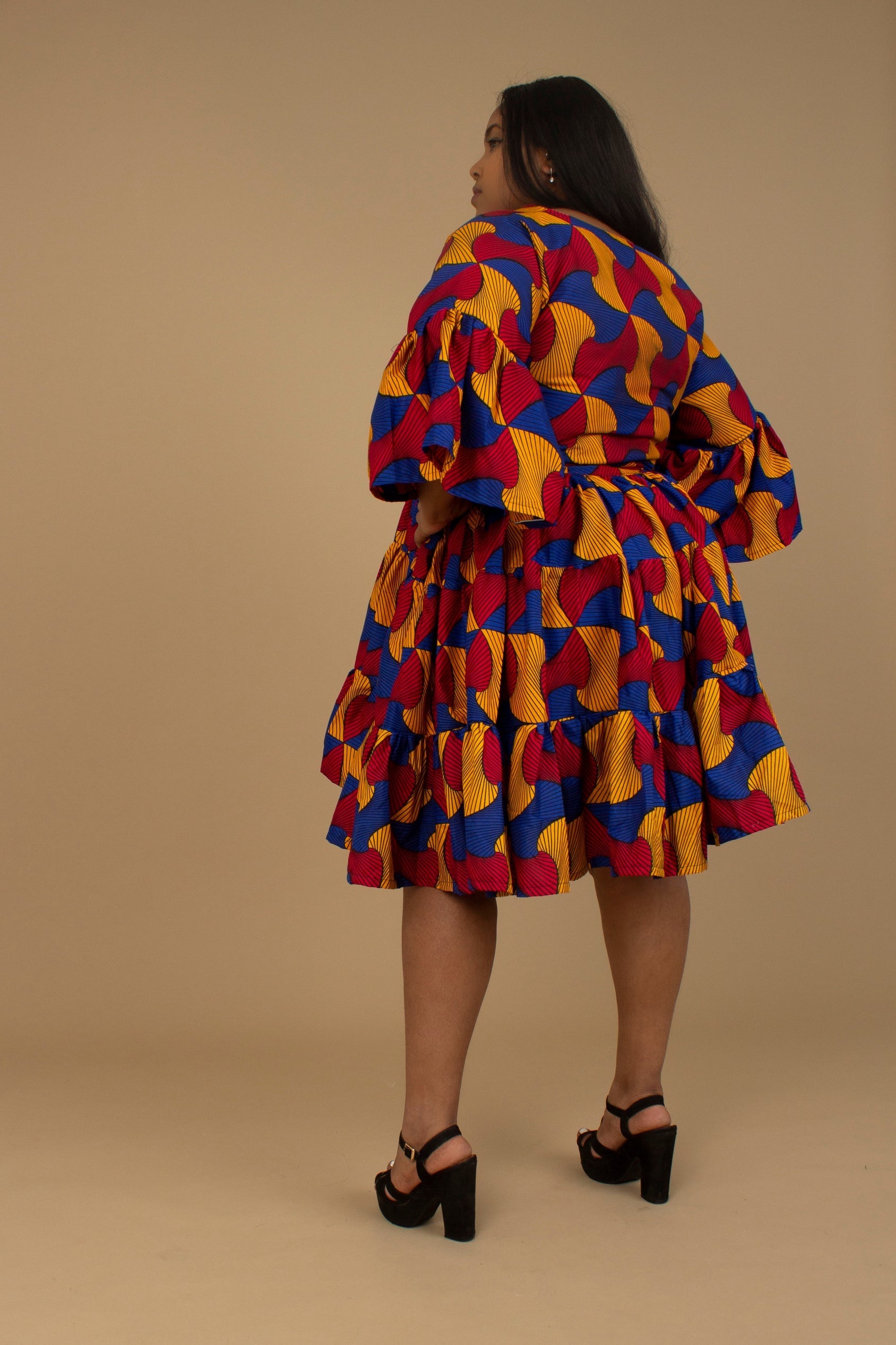 The Kano African Printed ruffled dress features an Ankara wax Print Belted Trim in a gorgeous blue, red and yellow multi-colored swirling geometric African Print pattern on sustainable cotton. Designed in England Made in Nigeria, Available in standard and plus sizes (UK 8-32). 