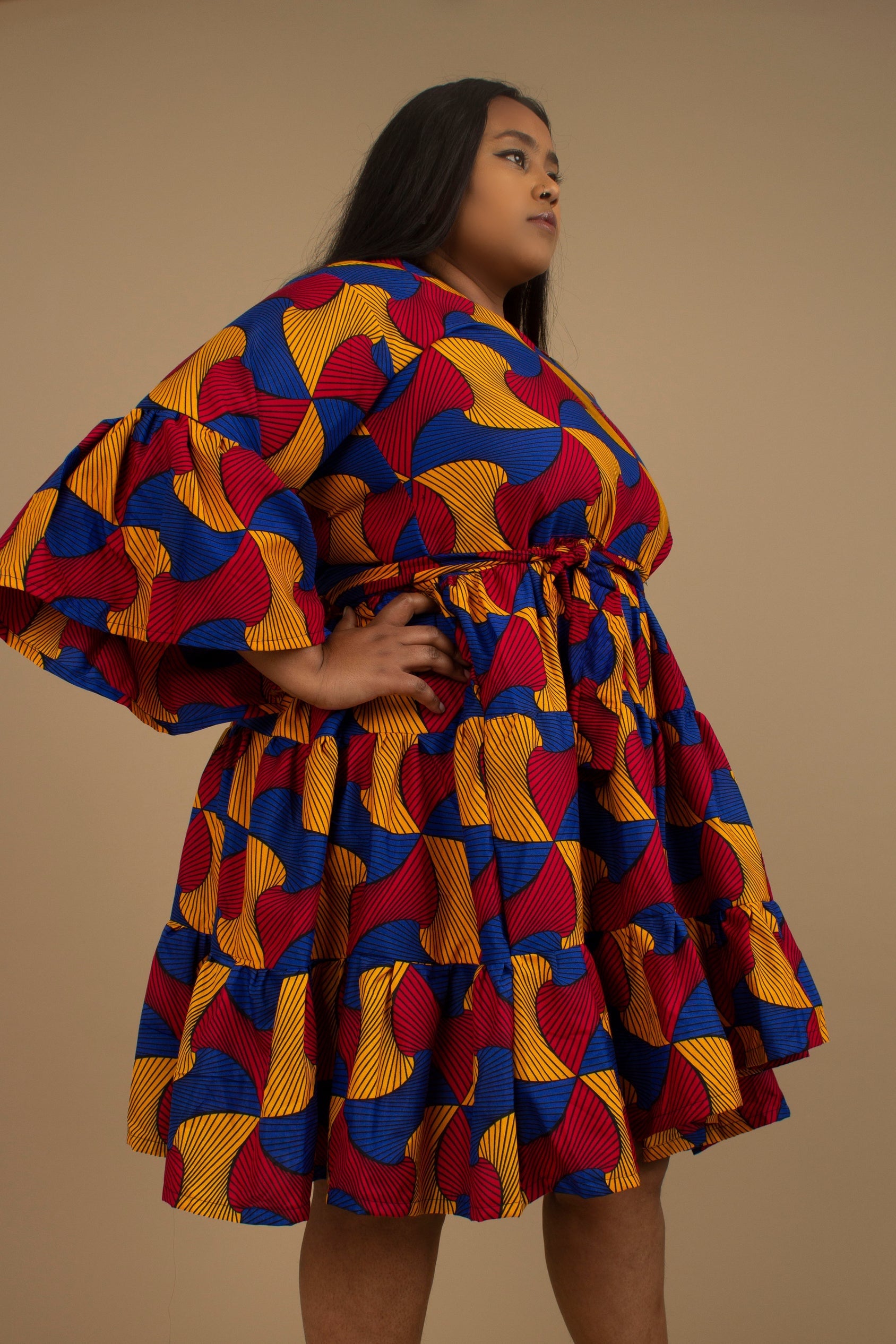 The Kano African Printed ruffled dress features an Ankara wax Print Belted Trim in a gorgeous blue, red and yellow multi-colored swirling geometric African Print pattern on sustainable cotton. Designed in England Made in Nigeria, Available in standard and plus sizes (UK 8-32). 