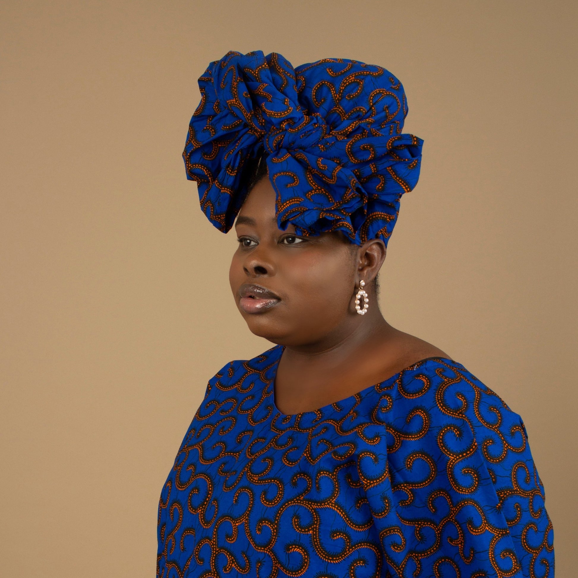 The Ore African Print Head Wrap is a lightweight African Print hair accessory that is ethically produced sourced cotton. The Ankara wax print in a gorgeous blue and orange swirling African Print pattern. Designed in England Made in Nigeria, Available Sizing: Small - 44" x 9" / 109cm x 22cm&nbsp; Large - 70" x 22" / 182cm x 55cm.
