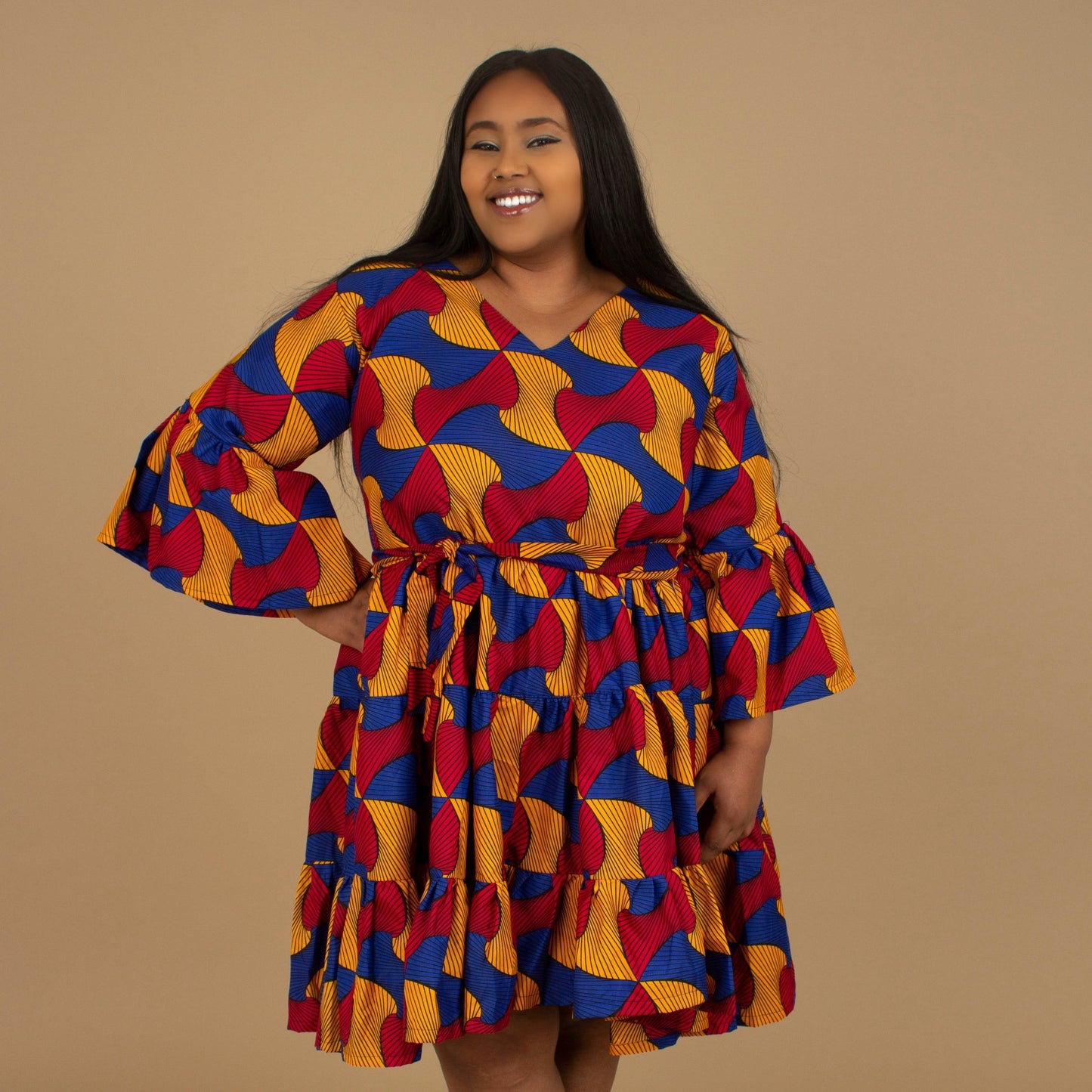 The Kano African Printed ruffled dress features an Ankara wax Print Belted Trim in a gorgeous blue, red and yellow multi-colored swirling geometric African Print pattern on sustainable cotton. Designed in England Made in Nigeria, Available in standard and plus sizes (UK 8-32). 