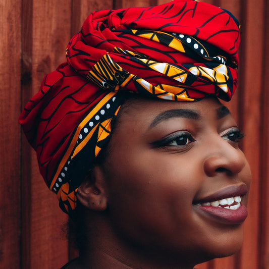 red, yellow, white, and black African print head wrap tied as a turban in a graphic pattern, made from sustainably sourced Ankara wax print.