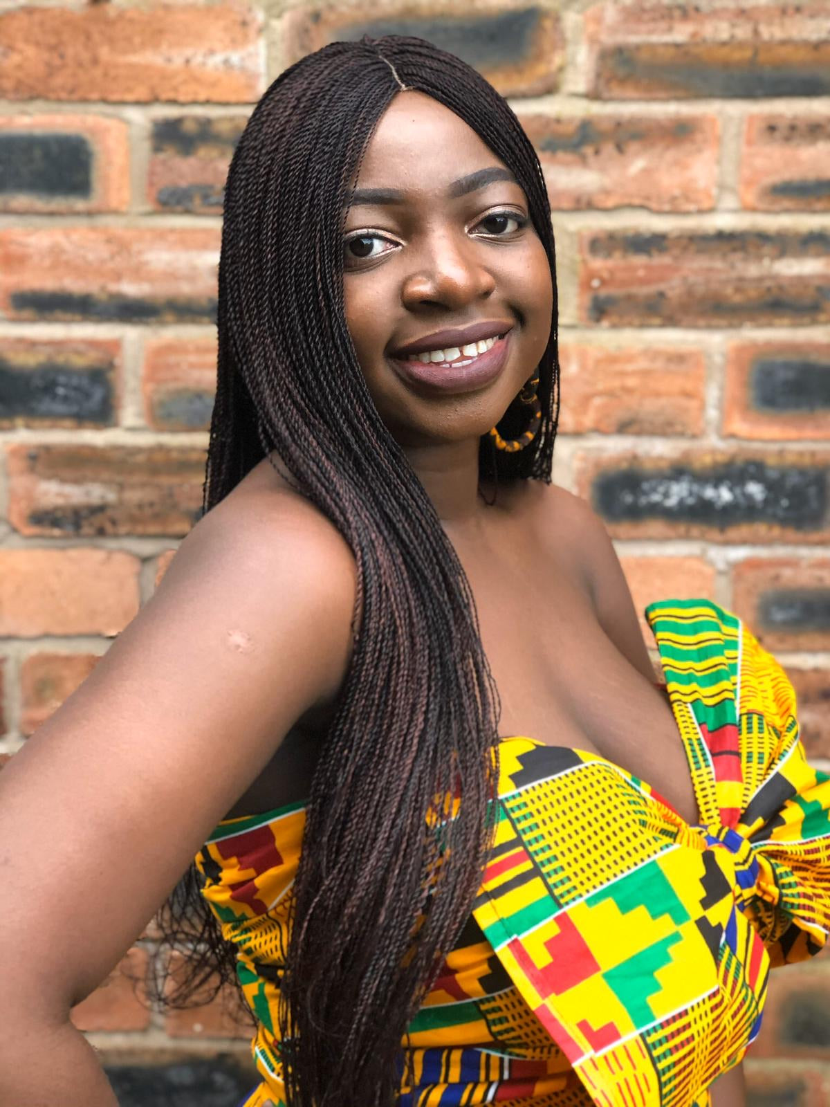 Yellow, green, red, and black African print head wrap tied as a accessory in a geo-shaped pattern, made from sustainably sourced Ankara wax print.