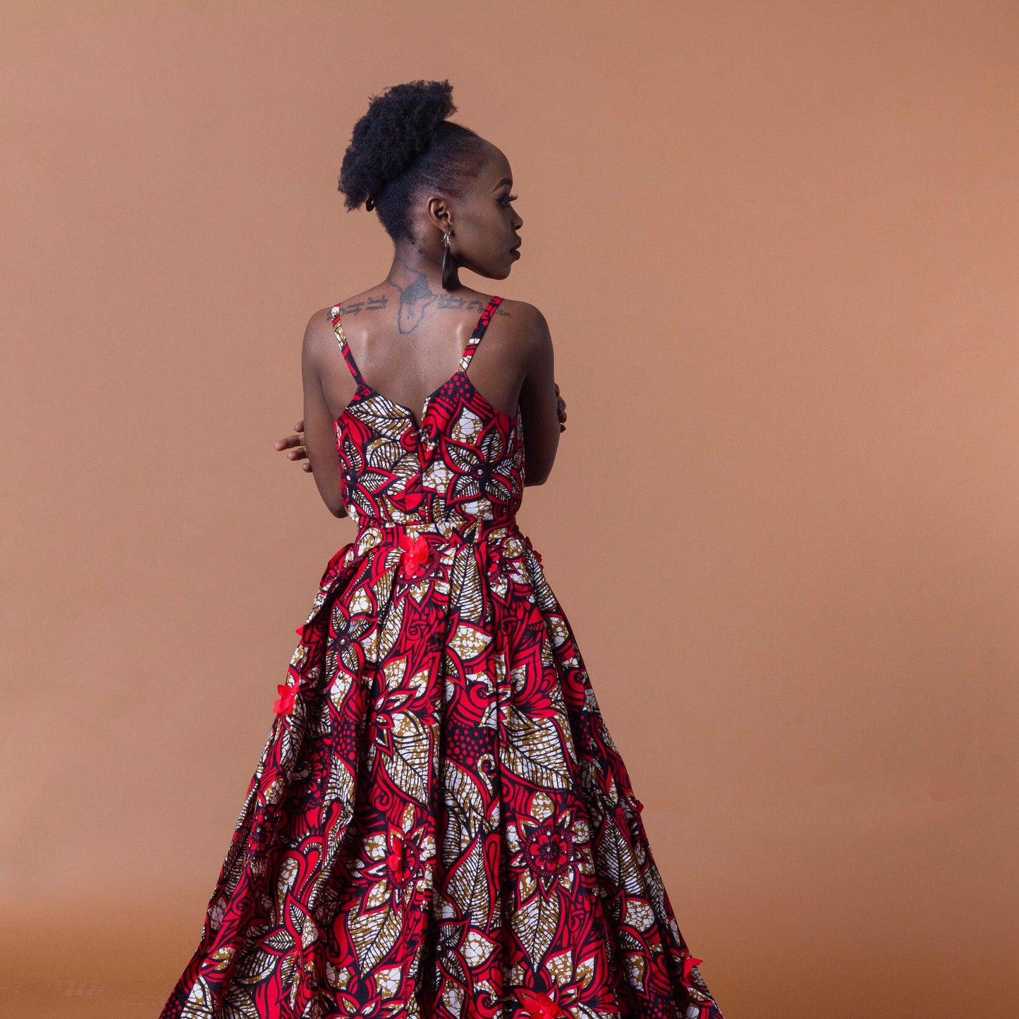 Ankara wax print in the bold African floral red, cream and light brown Ade fabric floor-length gown featuring a sweetheart neckline, closed back and off-shoulder straps with a matching outer cape belt.