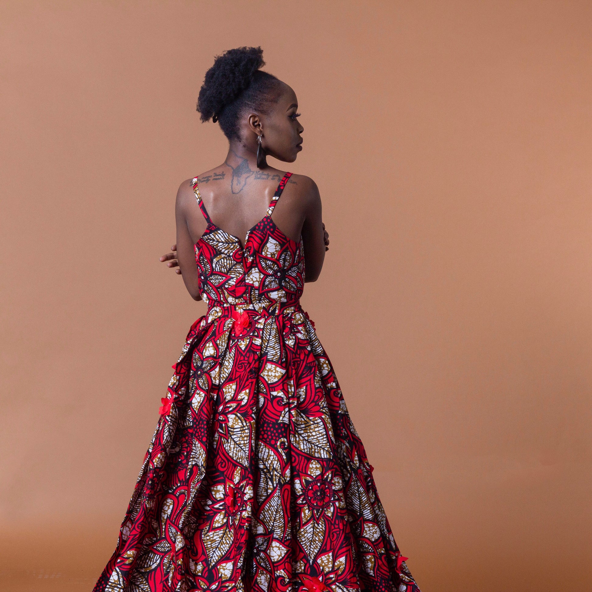 Ankara wax print in the bold African floral red, cream and light brown Ade fabric floor-length gown featuring a sweetheart neckline, closed back and off-shoulder straps with a matching outer cape belt.