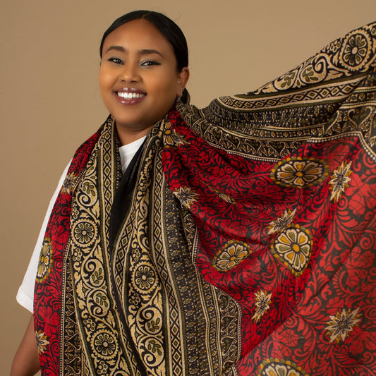 The one-sized Red Dashiki Chiffon Scarf is a vibrant floral African Print in an extremely flattering, red, gold and black African floral dashiki Print pattern. The Red Dashiki Chiffon Scarf is printed on a luxurious Chiffon that is ethically sourced, Designed in England Made in Nigeria. 