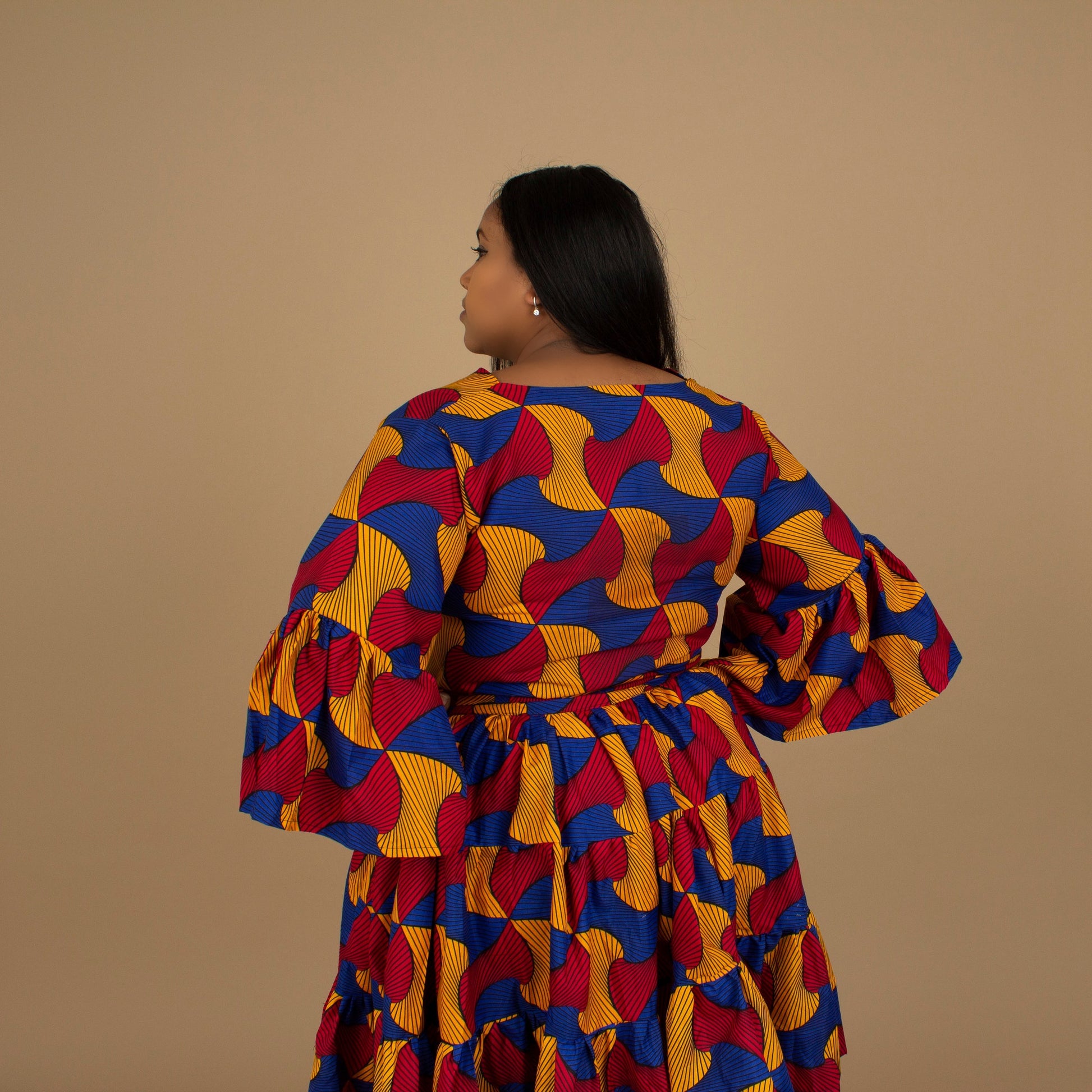 The Kano African Printed ruffled dress features an Ankara wax Print Belted Trim in a gorgeous blue, red and yellow multi-colored swirling geometric African Print pattern on sustainable cotton. Designed in England Made in Nigeria, Available in standard and plus sizes (UK 8-32). 