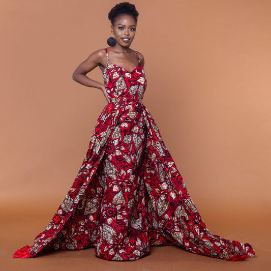 Ankara wax print in the bold African floral red, cream and light brown Ade fabric floor-length gown featuring a sweetheart neckline, closed back and off-shoulder straps with a matching outer cape belt.