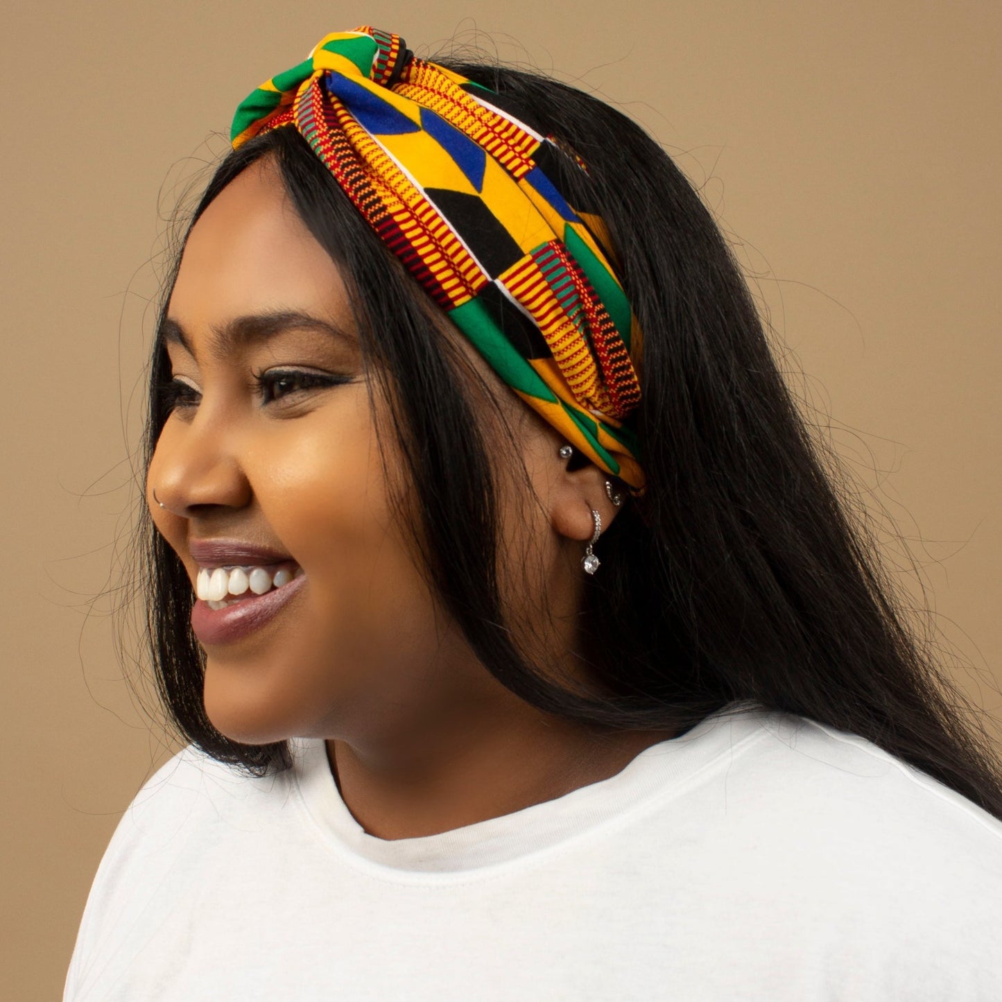 The one-sized Satin lined African Afua Kente Print on a Criss-Cross pre-tied Headband is handcrafted with sustainable cotton on a Ankara wax print in a traditional geometric multi-coloured Kente pattern. Designed in England Made in Ghana.
