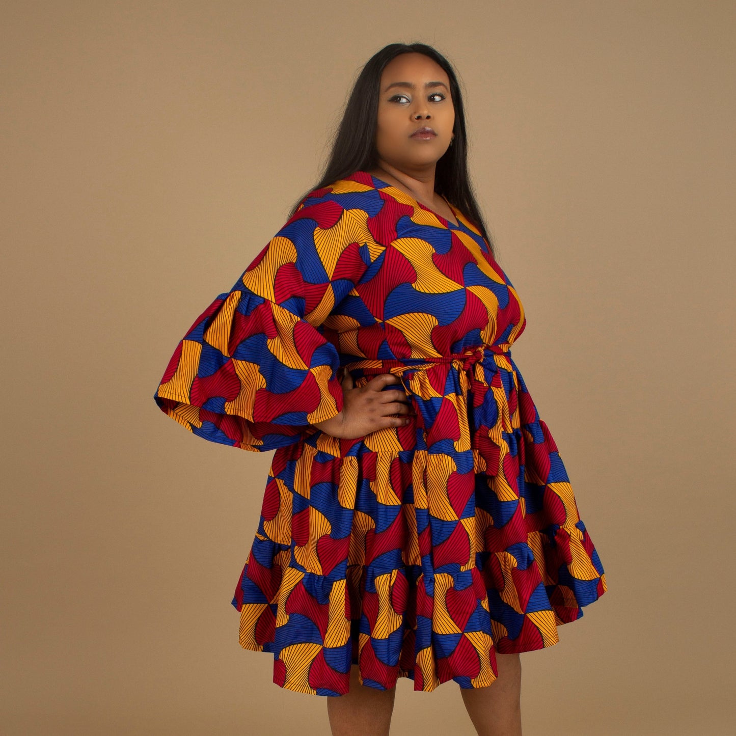 The Kano African Printed ruffled dress features an Ankara wax Print Belted Trim in a gorgeous blue, red and yellow multi-colored swirling geometric African Print pattern on sustainable cotton. Designed in England Made in Nigeria, Available in standard and plus sizes (UK 8-32). 
