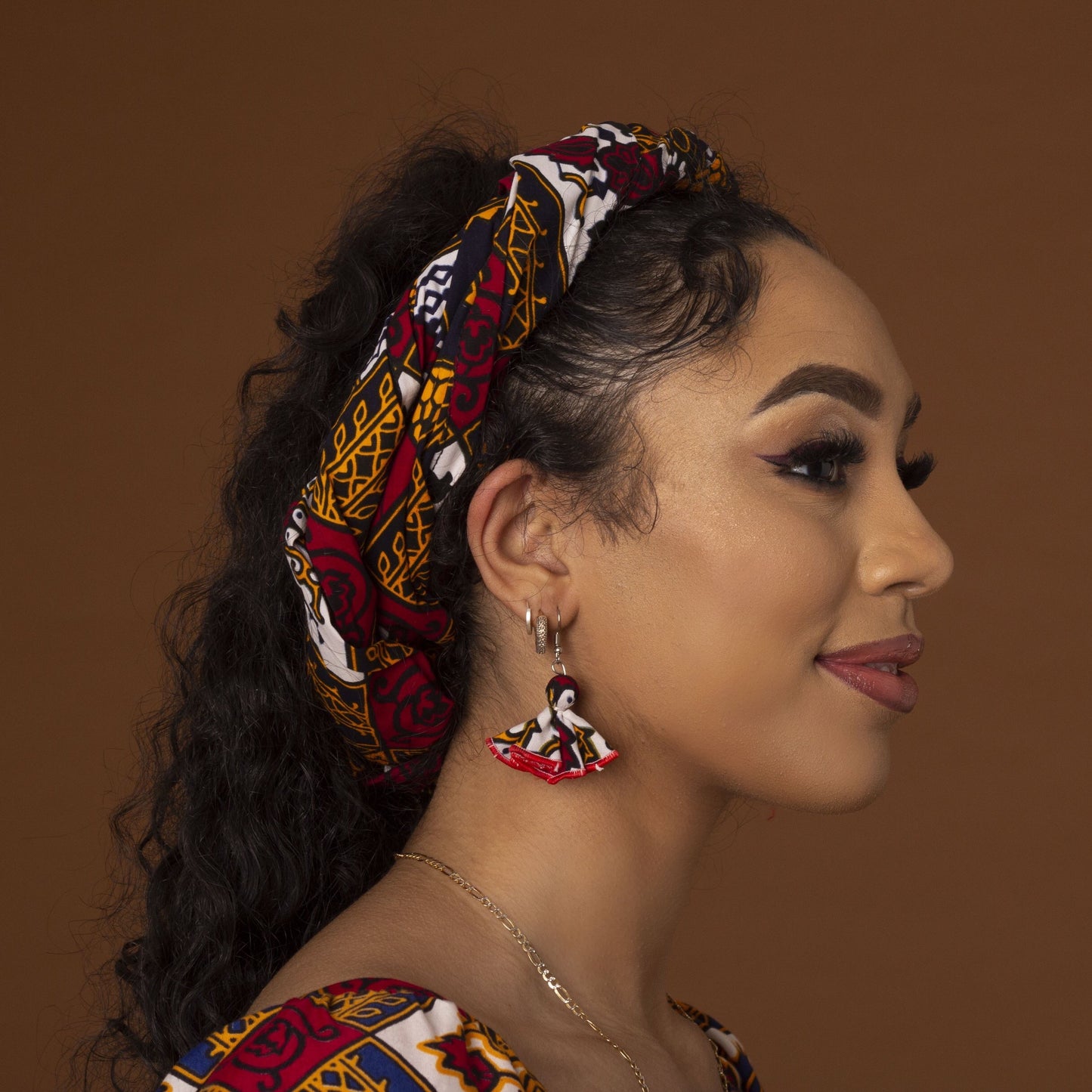 red, yellow, white, and black African print head wrap tied as a turban in floral medallion pattern, made from sustainably sourced Ankara wax print.