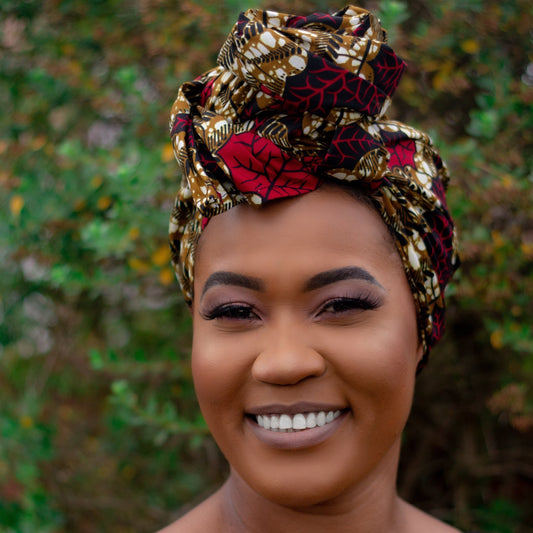 Brown, red, white, and black African print head wrap tied as a turban in a floral pattern, made from sustainably sourced Ankara wax print.